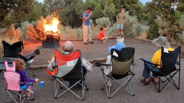 A family enjoys time together around a campfire at one of the campsites at Smoky Mountain Campground